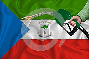 EQUATORIAL GUINEA flag Close-up shot on waving background texture with Fuel pump nozzle in hand. The concept of design solutions.