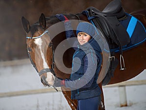 Equestrian country girl and her bay horse are in winter