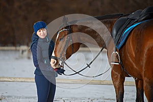 Equestrian country girl and her bay horse are in winter