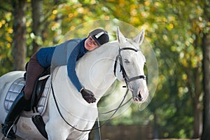 Equestrian lady hugging white horse neck