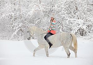Equestrian model girl walks horseback in the snowy woods