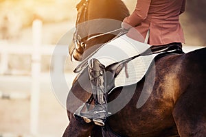 Equestrian sport. The leg of the rider in the stirrup, riding on a bay horse