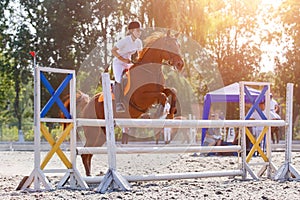 Equestrian sport. Young girl jumping over obstacle