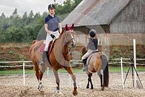 Equestrian sport - young girl rides on horse and little girl rides on pony in during training