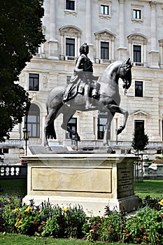 Equestrian statue, in the garden and park in the museum district, in Vienna, in front of a historic building with flowers on its f