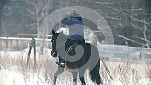 Equestrian woman in hat on horse riding in snowy field