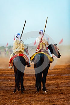 Equestrians participating in a traditional fancy event named Tbourida dressed in a traditional Moroccan outfit photo