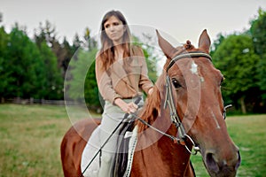Equine expedition. A charming female rider in beige blouse on her brown horse. Bond with animals, de-stress, and explore nature