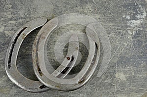 Equine them with old, worn horseshoes on a scratched and damaged steel background. Lots of texture with copy space.