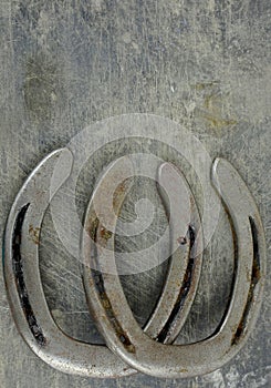 Equine them with old, worn horseshoes on a scratched and damaged steel background. Lots of texture with copy space.