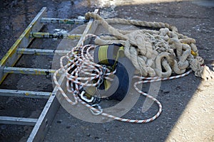 Equipment consisting of a ladder, ropes and a safety belt for working at high altitude lies on the asphalt