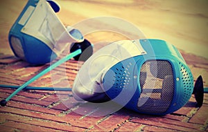 Equipment fencing mask and foil resting on the ground after the photo