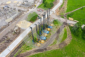 Equipment for installing piles in the ground, heavy machines for driving foundation pillars are lined up. Construction aerial view