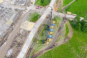 Equipment for installing piles in the ground, heavy machines for driving foundation pillars are lined up. Construction aerial view