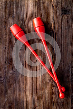Equipment for rhythmic gymnastics. Clubs on dark wooden background top view copy space
