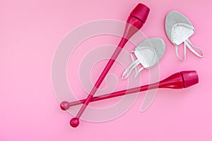 Equipment for rhythmic gymnastics. Clubs and gymnastics shoes on pink background top view on pink background top view