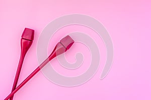 Equipment for rhythmic gymnastics. Clubs on pink background top view copy space