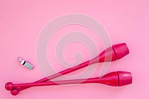 Equipment for rhythmic gymnastics. Clubs on pink background top view copy space