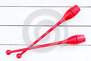 Equipment for rhythmic gymnastics. Clubs on white wooden background top view copy space