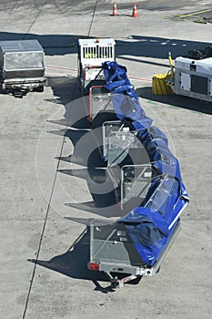 Equipment used by ground crews to load or unload and transport passenger baggage. Luggage trolleys on the airport tarmac.