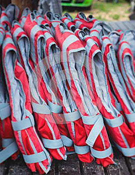 Equipment for water sports: bunch of wetsuits, paddles, red helmets and life jackets, preparing for rafting, kayaking, canoeying