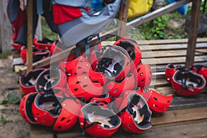 Equipment for water sports: bunch of wetsuits, paddles, red helmets and life jackets, preparing for rafting, kayaking, canoeying