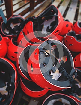 Equipment for water sports: bunch of wetsuits, paddles, red helmets and life jackets, preparing for rafting, kayaking, canoeying