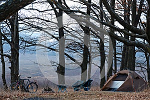 Equipped camp in the forest. Camping tent and portable chairs and aluminum table. Cold autumn day. concept of vacation and outdoor