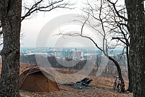 Equipped camp in the forest. Camping tent and portable chairs and table. Cold autumn day. outdoor. nobody. bonfire and bicycle,