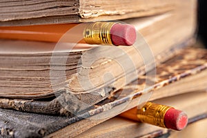 Eraser bound on a pencil and an old book. Writing accessories and books on an old table