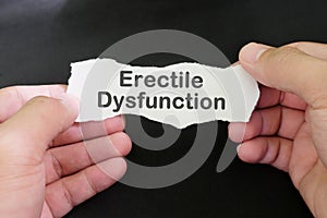 Erectile dysfunction diagnosis and anxiety concept. Male hand holding paper with written word text in black background.