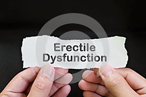 Erectile dysfunction diagnosis and anxiety concept. Male hand holding paper with written word text in black background.