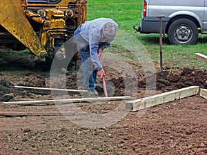 Erecting a Fence Man digging holes with spade and yellow digger