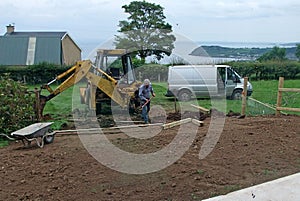 Erecting a Fence Man digging holes with spade and yellow digger