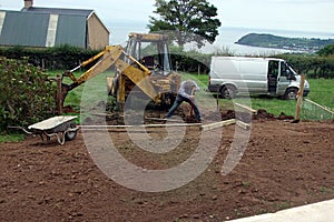 Erecting a Fence Man digging holes with spade and yellow digger