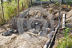 Erecting a field stones wall using wooden formwork