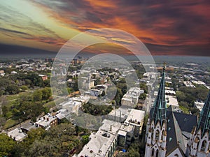 erial shot of the office buildings, apartments and shops in the city skyline surrounded by a river, lush green trees, roads and photo