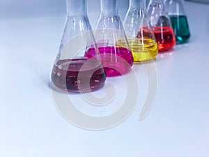 The Erlenmeyer or Conical flask on bench laboratory, with colorful solvent solution from titration experiment, acidity, alkalinity