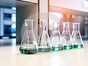 The Erlenmeyer or Conical flasks on bench laboratory, with range of green solvent forming reaction between boric acid and ammonia.