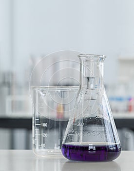 Erlenmeyer Flask contains purple liquid chemicals on a white laboratory table