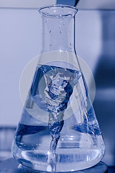 Erlenmeyer flask spinning in bioscience laboratory mixer. Concept of science, laboratory and study of diseases