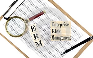 ERM - Enterprise Risk Management text on wooden block on a chart background