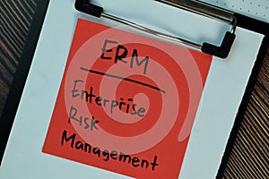 ERM - Enterprise Risk Management write on sticky notes isolated on Wooden Table