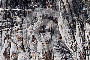 Eroded cracked granite cliff in multiple gray shades