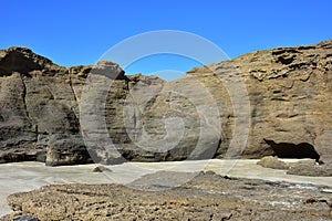 Eroded Rocky Cliff On Sandy Beach
