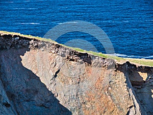 Eroding soil, subsoil and bedrock shown on sheer cliffs near Uyea in Northmavine, Shetland, UK. photo