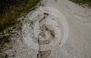 erosion grooves after rains in a dirt road. deep ground after a storm. lack of