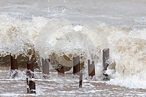 Erosion. Metal groyne posts being eroded by a sea wave