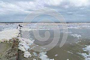 Erosion seawall covered in heavy sea foam, rough surf and storm clouds