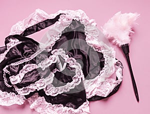 Erotic maid costume. Satin silk black white lace. Pink background